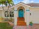 Inviting home entrance with a bright blue door, terracotta tile steps and lush tropical landscaping at 400 Coronado Dr, Punta Gorda, FL 33950
