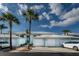 Light blue condo building featuring private garages, landscaping, and a bright blue, partly cloudy sky at 5738 Sabal Trace Dr # 204B57, North Port, FL 34287