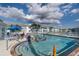 Inviting community pool with lounge chairs, umbrellas, and surrounding buildings in the distance at 5738 Sabal Trace Dr # 204B57, North Port, FL 34287