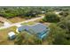 Aerial view of the blue house showcasing a screened pool, a large gray roof, and a storage shed at 9 Logan St, Port Charlotte, FL 33954