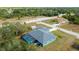 Aerial view of the blue property featuring a screened pool, a large gray roof, and a storage shed in the backyard at 9 Logan St, Port Charlotte, FL 33954