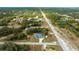 Aerial view of the property showcasing a screened pool and a large gray roof in a lush green neighborhood at 9 Logan St, Port Charlotte, FL 33954