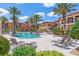 Resort-style pool with lounge chairs, tables, umbrellas, and tropical landscaping at 91 Vivante Blvd # 402/9142, Punta Gorda, FL 33950