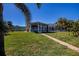 Pathway to screened patio, lush lawn, palm trees at 125 Ott Cir, Port Charlotte, FL 33952