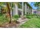 Outdoor patio with table and chairs extends from the rear of the townhome with lush green grass and foliage at 1710 Starling Dr # 102, Sarasota, FL 34231