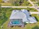 A close aerial view of the home highlighting the screened-in pool, metal roof, and well-kept lawn at 18181 Bly Ave, Port Charlotte, FL 33948