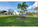 Exterior view of the back yard showcasing a screened-in porch, mature landscaping, and a well-maintained lawn at 18181 Bly Ave, Port Charlotte, FL 33948