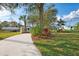 Lush front yard with a winding concrete driveway, mature trees and tropical landscaping, creating a welcoming entrance at 18181 Bly Ave, Port Charlotte, FL 33948