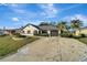 Inviting home with a long driveway, gray roof, and a landscaped front yard under a bright sky at 20352 Tappan Zee Dr, Port Charlotte, FL 33952