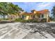 Tan colored house with red tile roof, landscaping and a long driveway at 21370 Harborside Blvd, Port Charlotte, FL 33952