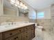 Bathroom featuring a double sink vanity, stone tile walls, a toilet, and an elegant framed mirror at 21402 Meehan Ave, Port Charlotte, FL 33952