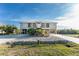 Front exterior view of a two-story coastal home with a metal roof, double balconies, and well-maintained landscaping at 24343 Pirate Harbor Blvd, Punta Gorda, FL 33955