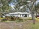 Landscaped yard with a white house and large trees at 2771 Siesta Dr, Venice, FL 34293