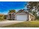 View of the beige home with a spacious driveway, white garage door, and well-maintained landscaping at 336 Japura St, Punta Gorda, FL 33983