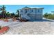 Beautiful coastal home with brick driveway, tropical landscaping, and stairs leading to the elevated entry at 37 Bocilla Dr, Placida, FL 33946