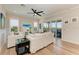 Sunlit living room with white sofas, a ceiling fan, and sliding doors to the balcony at 37 Bocilla Dr, Placida, FL 33946