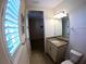 Neutral bathroom with granite-topped vanity, mirror, and shuttered window allowing natural light to come in at 10311 Lands End Cir # 16, Placida, FL 33946