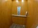 Interior of a residential elevator featuring wood paneling, a control panel, handrail, and non-slip flooring at 10311 Lands End Cir # 16, Placida, FL 33946