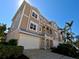 Exterior view of the tan three-story condo building, highlighting its large windows, garage and well-manicured landscaping at 10311 Lands End Cir # 16, Placida, FL 33946