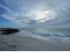 Ocean waves roll onto a beach with few people under a cloudy sky at 10421 Coral Landings Ln # 107, Placida, FL 33946