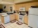 Bright kitchen with wooden cabinets, white appliances, and decorative rugs at 1186 Rio De Janeiro Ave # 106, Punta Gorda, FL 33983