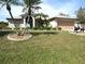 Charming home featuring a two-car garage, well-manicured lawn, and decorative landscaping with palm trees at 1247 Petronia St, North Port, FL 34286