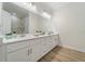 Bathroom boasts dual sinks, white cabinets, a large mirror, and modern lighting fixtures at 13356 Rayburn Ln, Port Charlotte, FL 33981