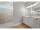 Well-lit bathroom featuring modern vanity, large mirror, and walk-in shower with marble tiling and natural light at 13364 Rayburn Ln, Port Charlotte, FL 33981