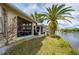 Waterfront home featuring a screened-in patio and lush landscaping with several mature palms at 1706 Fountain View Cir, Venice, FL 34292