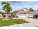 Inviting home featuring an attached garage, lush lawn, and mature palm trees at 1706 Fountain View Cir, Venice, FL 34292