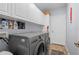 Well-lit laundry room with gray washer and dryer with ample storage at 1706 Fountain View Cir, Venice, FL 34292