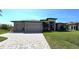 A single-story home features a well manicured lawn, brick paver driveway and three-car garage at 17350 Bayharbor Cir, Port Charlotte, FL 33948