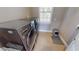 Functional laundry area featuring gray front load washer and dryer set, tiled floor, and natural light at 17350 Bayharbor Cir, Port Charlotte, FL 33948