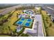Aerial view of community tennis courts featuring four courts, a clubhouse, and lush landscaping in a well-maintained community at 1912 Saddlewood Cir, Port Charlotte, FL 33953