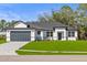Charming home featuring a gray garage door, lush green lawn, and neat front yard landscaping at 2143 S Haberland Blvd, North Port, FL 34288