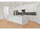 Elegant kitchen with white cabinets, stainless steel appliances, and a spacious island, seamlessly integrated with living area at 2143 S Haberland Blvd, North Port, FL 34288