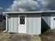 Outbuilding with white door and diamond pane window detailing; blue exterior at 21535 Edgewater Dr, Port Charlotte, FL 33952