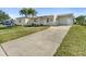 Wide driveway leading to a cozy home with a well-kept lawn and a charming front entrance at 21923 Cellini Ave, Port Charlotte, FL 33952