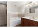 A well-lit bathroom featuring a soaking tub, tile accents, a shower with a glass door, and vanity with wood finish at 2443 Lake View Blvd, Port Charlotte, FL 33948