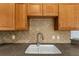 Up-close view of a kitchen sink, showcasing the wood cabinets and tiled backsplash for added detail at 2443 Lake View Blvd, Port Charlotte, FL 33948