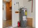 Water heater with visible safety labels, nearby fire extinguisher, and utility connections in a garage or utility area at 2443 Lake View Blvd, Port Charlotte, FL 33948