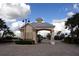 Community entrance gatehouse featuring a peaked roof, pillars, and well-maintained landscaping at 24576 Buckingham Way, Punta Gorda, FL 33980