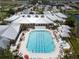 Aerial view of a large outdoor pool with lounge chairs, umbrellas, and a jacuzzi at the community center at 24576 Buckingham Way, Punta Gorda, FL 33980