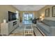 Bright living room with a large television, comfortable seating, and access to the balcony at 25100 Sandhill Blvd # J-201, Punta Gorda, FL 33983