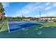 View of the community's tennis court with blue and green surfaces and shaded picnic area at 25100 Sandhill Blvd # J-201, Punta Gorda, FL 33983