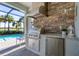 Outdoor kitchen with a built-in grill and granite countertops by the pool at 25186 Keygrass Ct, Punta Gorda, FL 33955