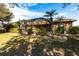 Exterior view of the home featuring a screened-in patio, manicured landscaping, and mature palm trees at 27199 Punta Cabello Ct, Punta Gorda, FL 33983