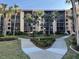 Multi-story building surrounded by sidewalks, lush landscaping, and mature palm trees at 3006 Caring Way # 409, Port Charlotte, FL 33952