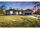 Charming single story house with gray exterior, attached garage, and green lawn at sunset at 4175 Horseshoe Ave, North Port, FL 34286
