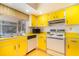 Sunny kitchen with vintage yellow cabinetry, white appliances and plenty of natural light at 4254 Bur St, Port Charlotte, FL 33948